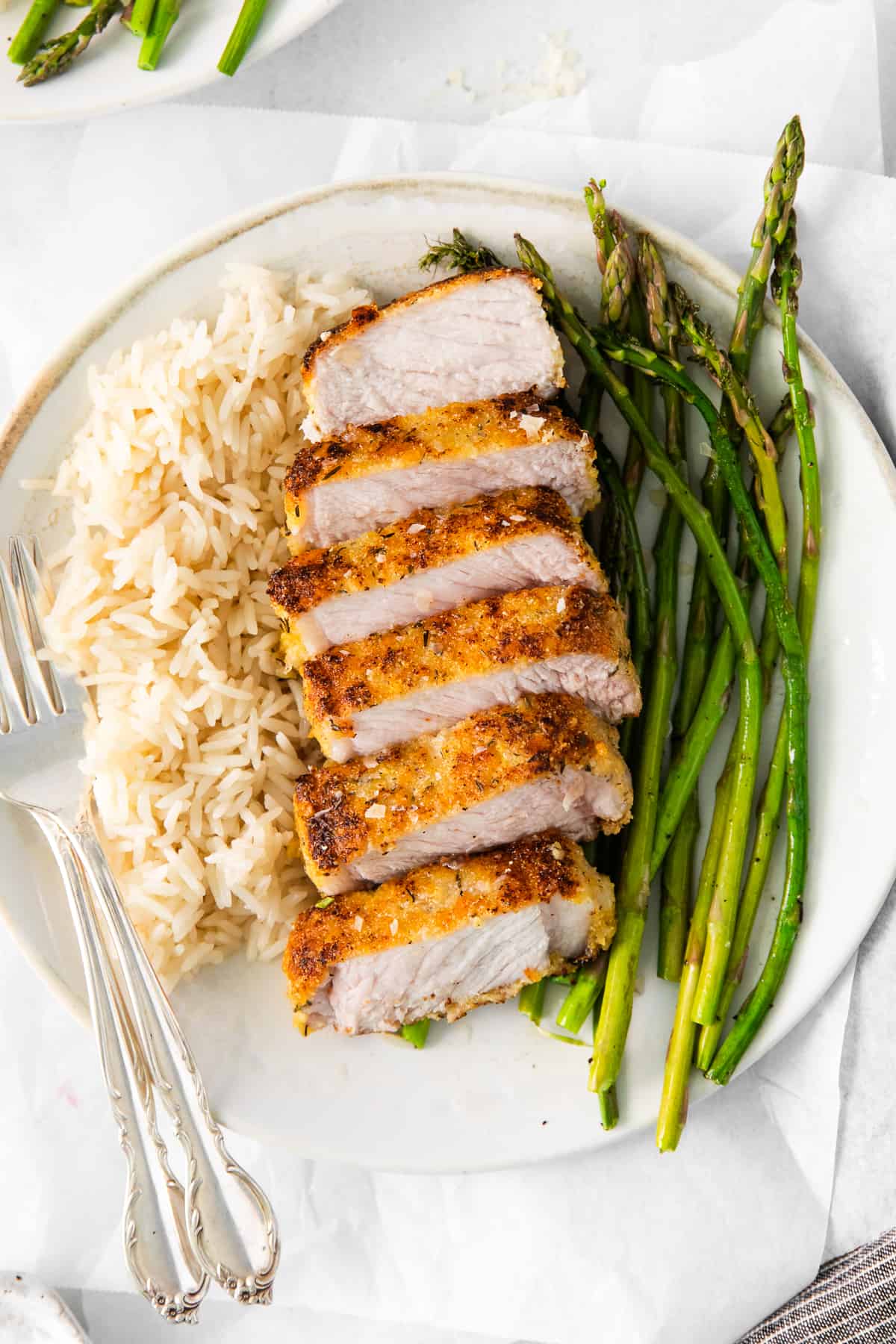 Pork chops, asparagus, and rice on a plate.