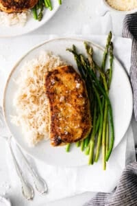 Pork chop on a plate with asparagus and rice.