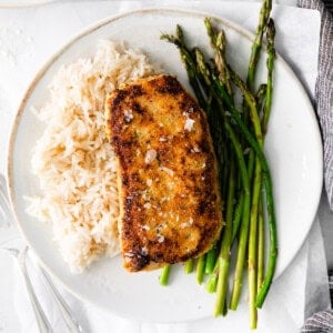 Pork chop on a plate with asparagus and rice.