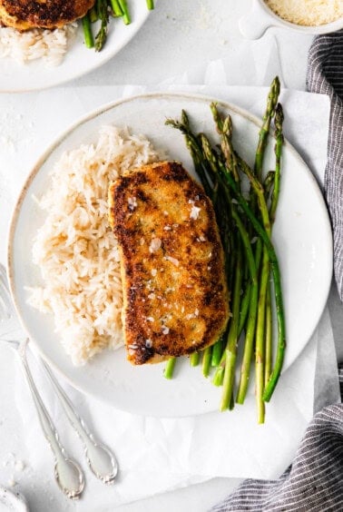 Pork chop on a plate with asparagus and rice.