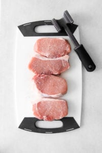 Pork chops on a cutting board.