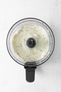 a food processor filled with a white sauce.