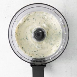 a food processor filled with a white sauce.