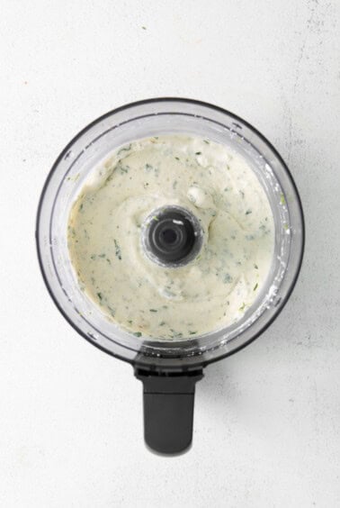 a food processor filled with a white sauce.