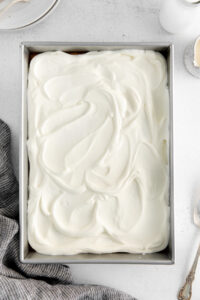 a cake in a metal pan with whipped cream on top.