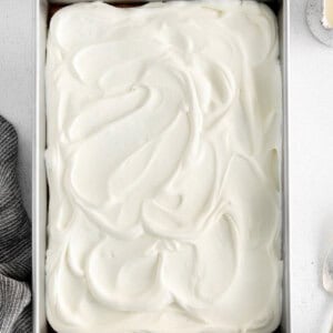 a cake in a metal pan with whipped cream on top.