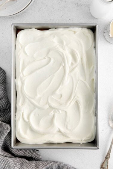 a cake in a metal pan with whipped cream on top.