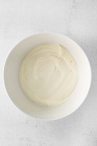 whipped cream in a bowl on a white surface.