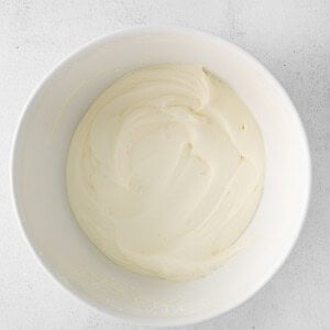 whipped cream in a bowl on a white surface.