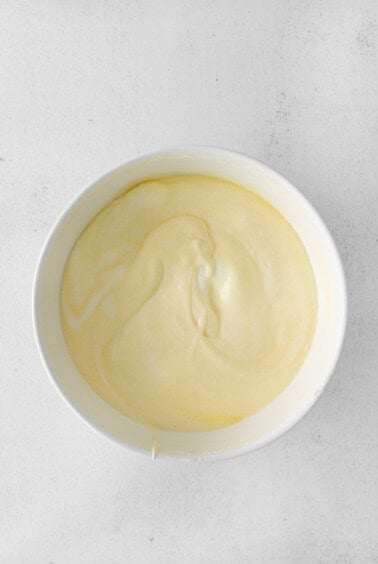 whipped cream in a white bowl on a white surface.