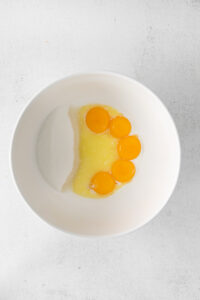 three eggs in a bowl on a white surface.