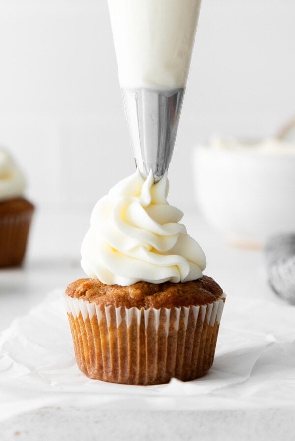 a cupcake being frosted with whipped cream.