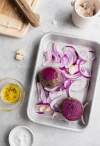 a baking sheet of beets, purple onion and garlic