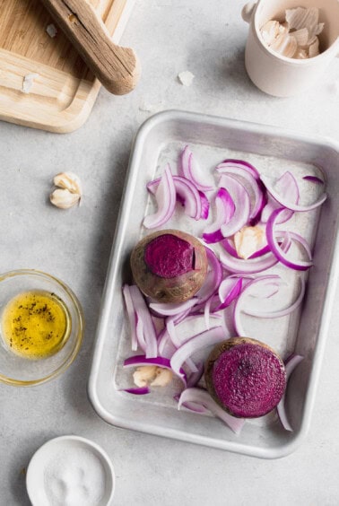 a baking sheet of beets, purple onion and garlic