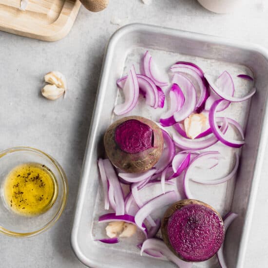 a baking sheet of beets, purple onion and garlic