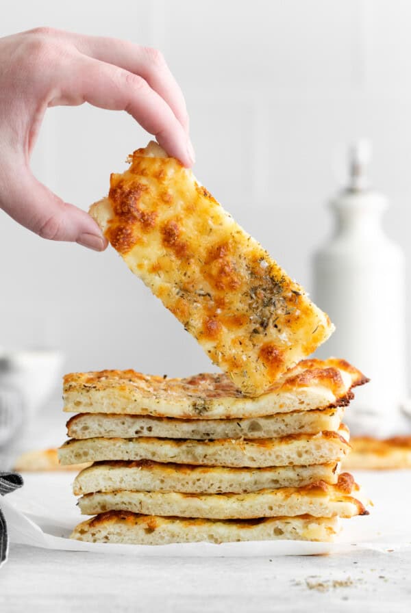 A person grabbing cheese from a stack of bread.