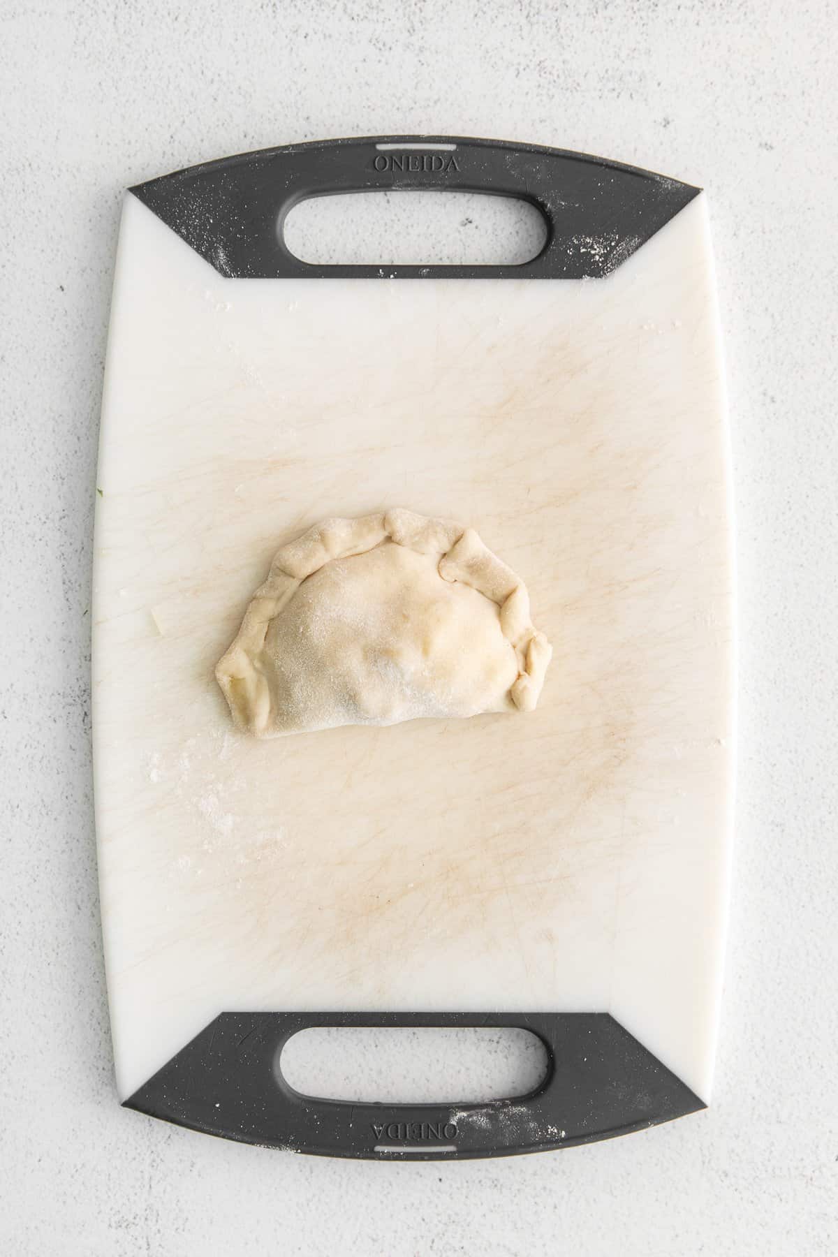 uncooked empanada on cutting board.