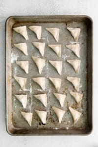 Folded cheese tortellini on a pan.