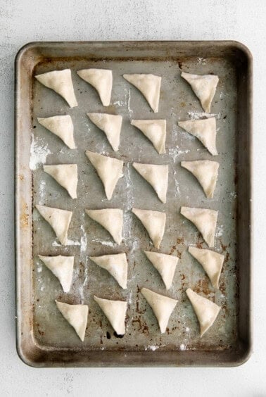 Folded cheese tortellini on a pan.