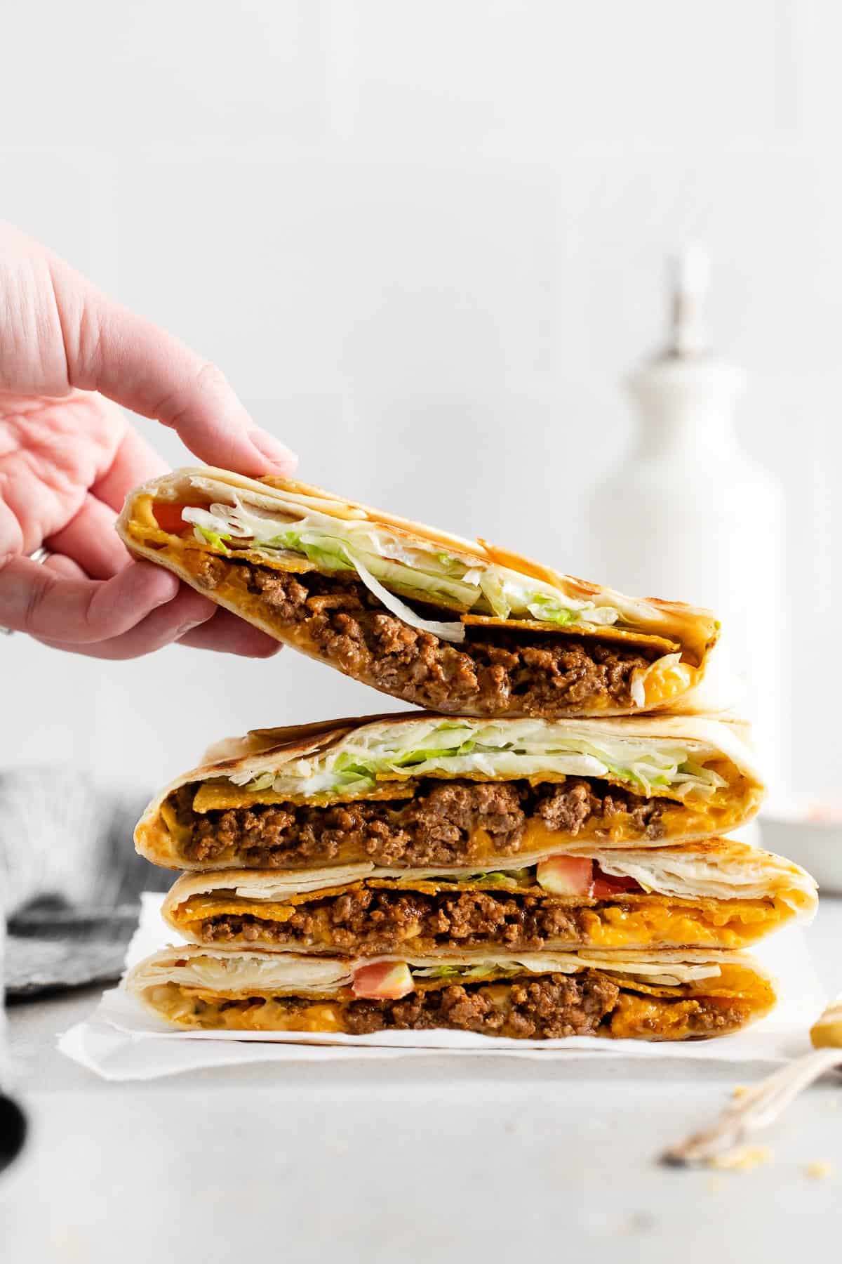 Crunchwrap supreme stacked 4 high on a plate.