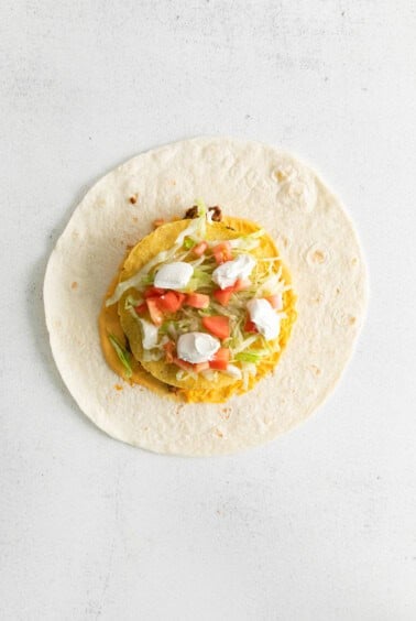 a tortilla filled with vegetables and cheese on a white background.