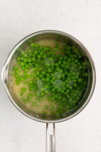 peas in a pan on a white surface.