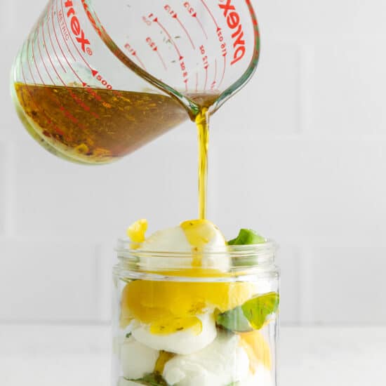 Pouring olive oil into a jar with goat cheese.