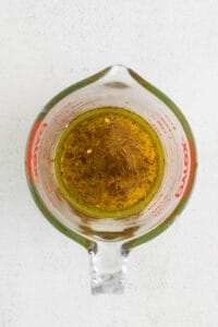 olive oil in a measuring cup on a white background.