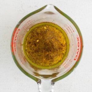 olive oil in a measuring cup on a white background.