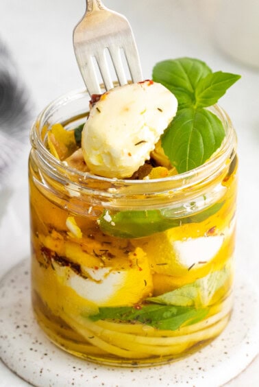 Taking a piece of goat cheese out of the jar.