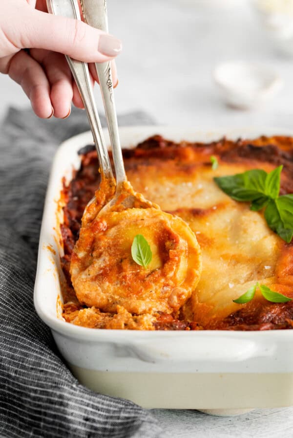 a person taking a fork out of a lasagna dish.