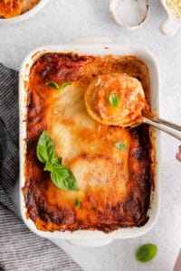 lasagna in a white dish with a spoon.