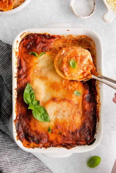 lasagna in a white dish with a spoon.