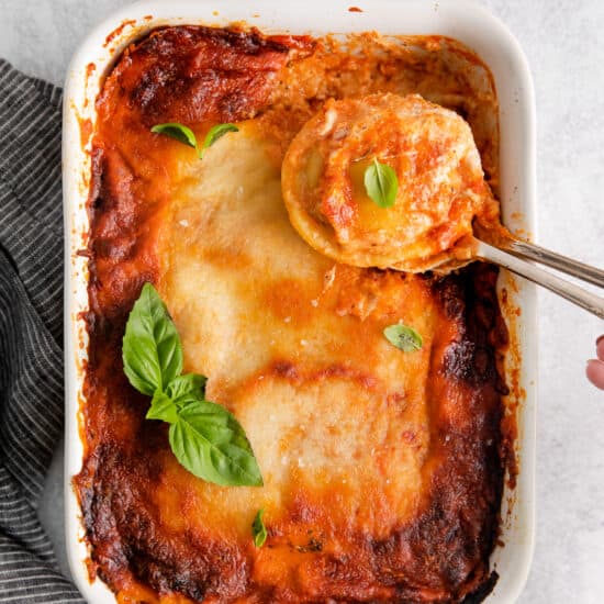 lasagna in a white dish with a spoon.