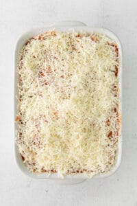 a white casserole dish with a layer of cheese on top.