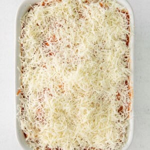 a white casserole dish with a layer of cheese on top.