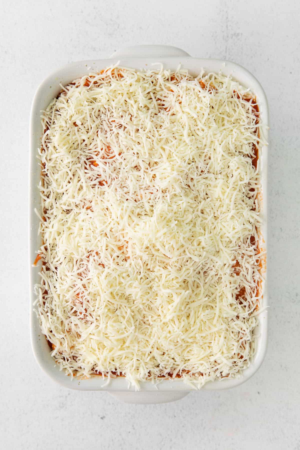 Ravioli lasagna covered in shredded mozzarella cheese.