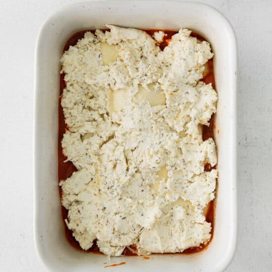 a white baking dish filled with a cheesy dish.