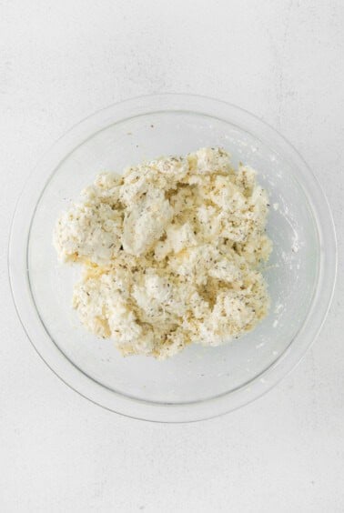 cauliflower in a glass bowl on a white surface.