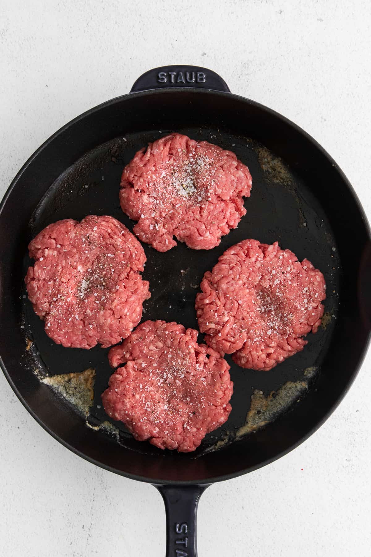 Beef patties in a cast iron skillet.