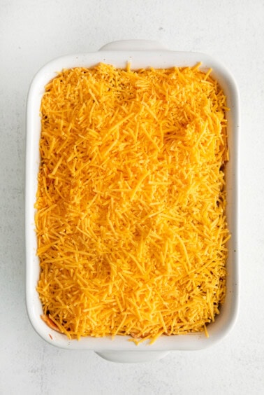 a casserole dish filled with shredded cheese.