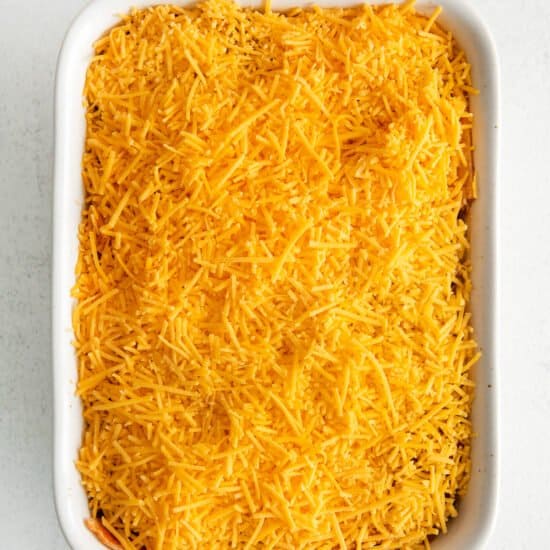 a casserole dish filled with shredded cheese.