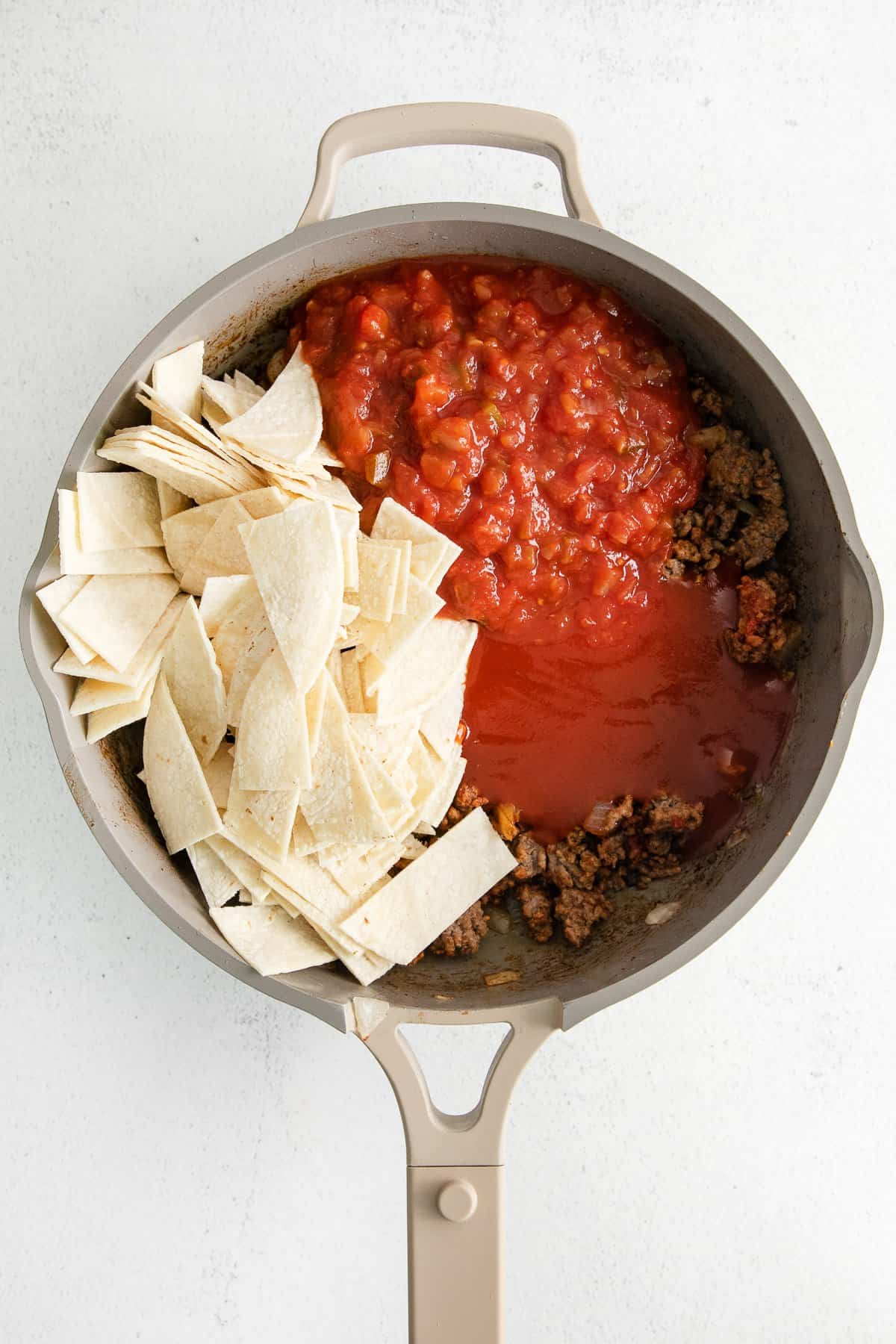 Salsa and tortillas in a skillet for taco bake.