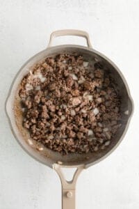 a skillet filled with ground beef and onions.