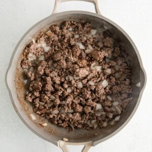 a skillet filled with ground beef and onions.