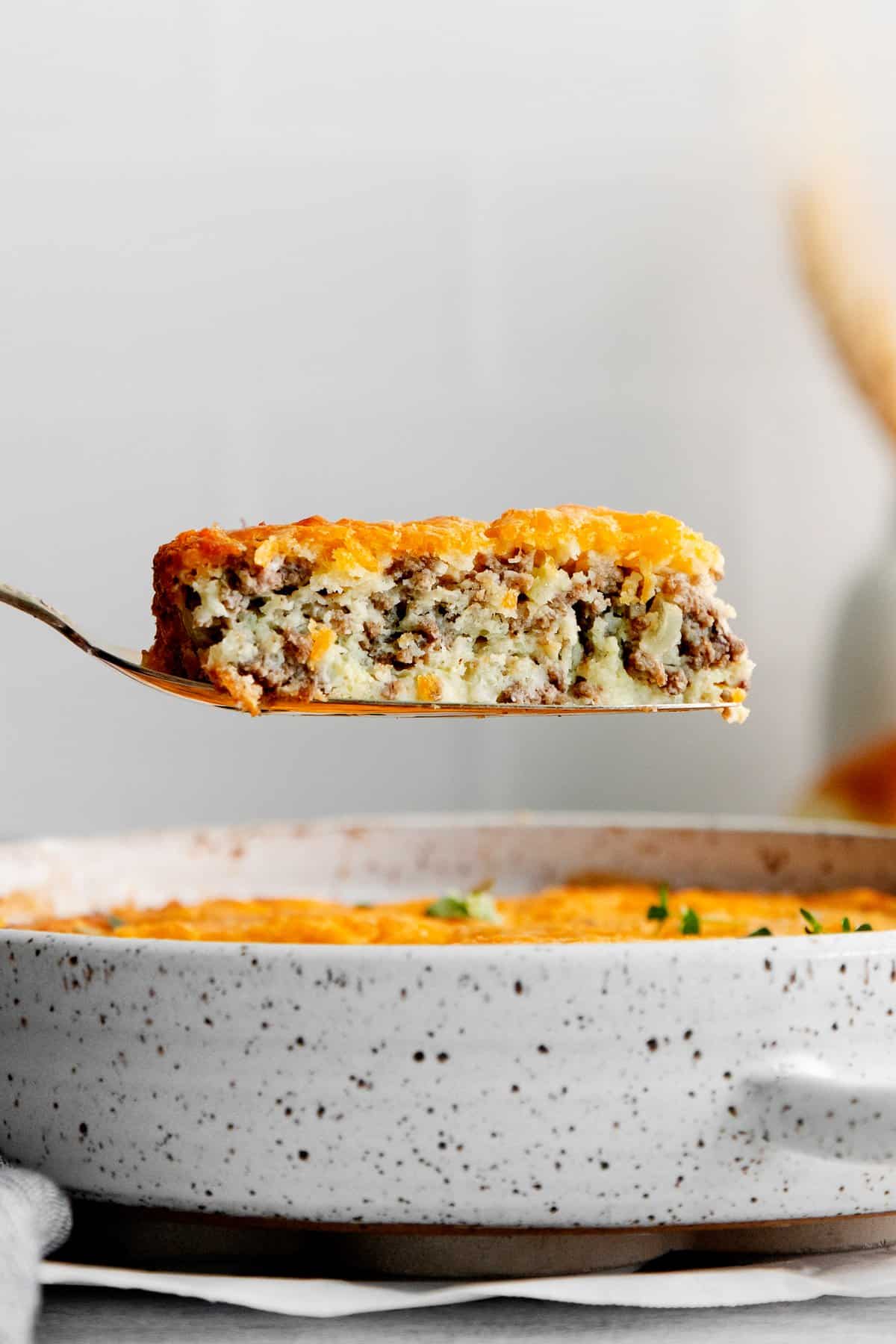 A slice of cheeseburger pie on a spatula. 