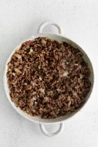 Ground beef and onion in a casserole dish.