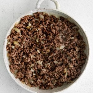 Ground beef and onion in a casserole dish.