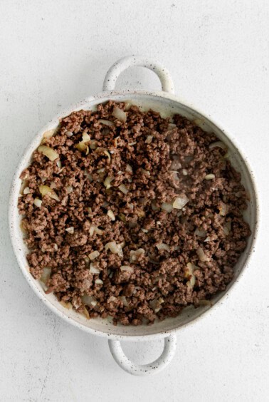 Ground beef and onion in a casserole dish.