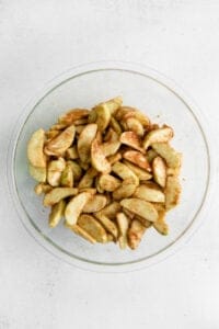 apple slices in a glass bowl on a white background.